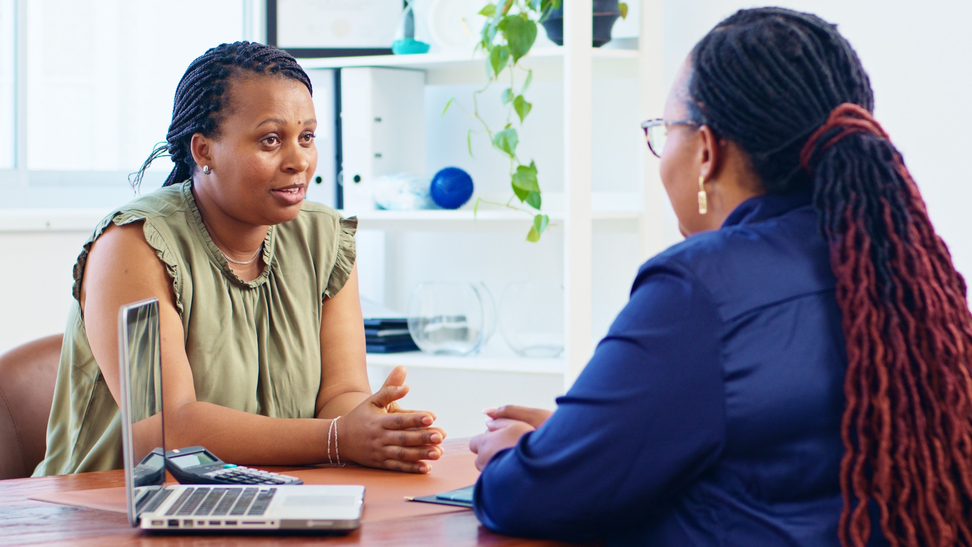 Professional Consultation Between Two Women in Modern Office Setting with Focused Discussion
